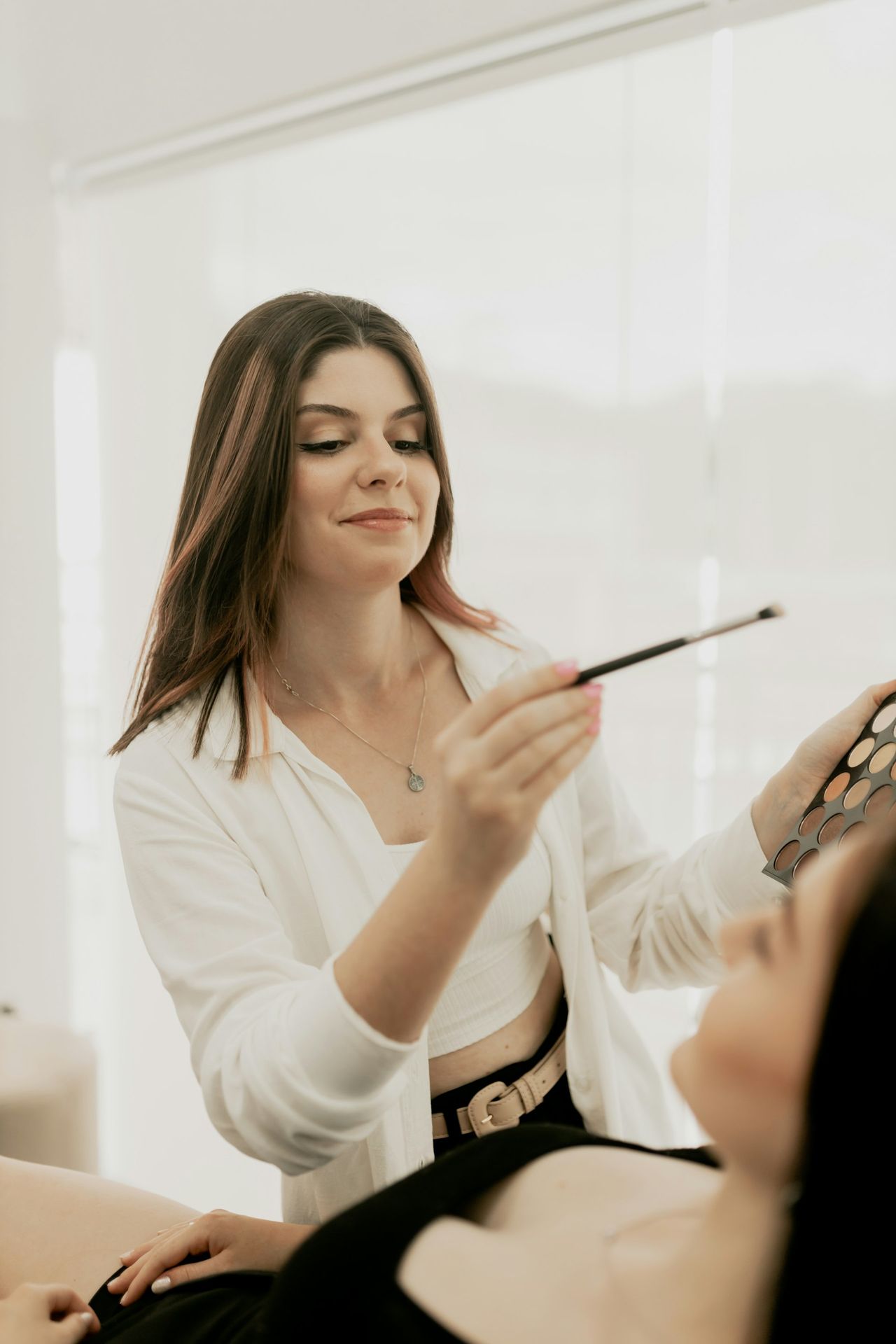 A woman getting her makeup done in a room